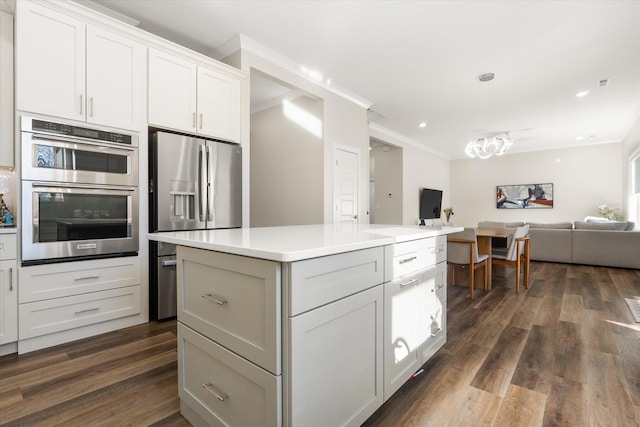 kitchen with white cabinets, crown molding, dark hardwood / wood-style floors, a kitchen island, and stainless steel appliances