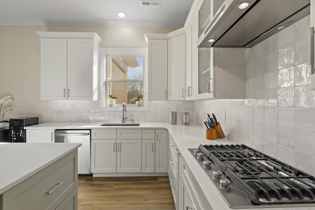 kitchen featuring white cabinets, appliances with stainless steel finishes, sink, and wall chimney range hood