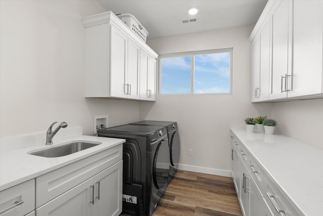 washroom featuring washing machine and dryer, cabinets, sink, and dark wood-type flooring