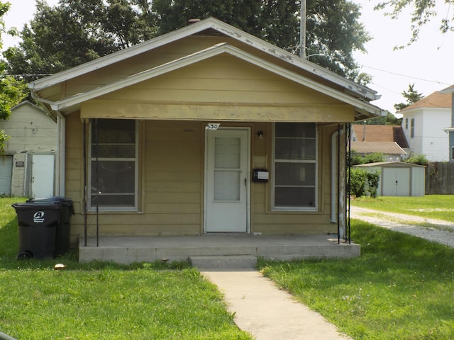 bungalow-style home featuring a front yard and a storage shed