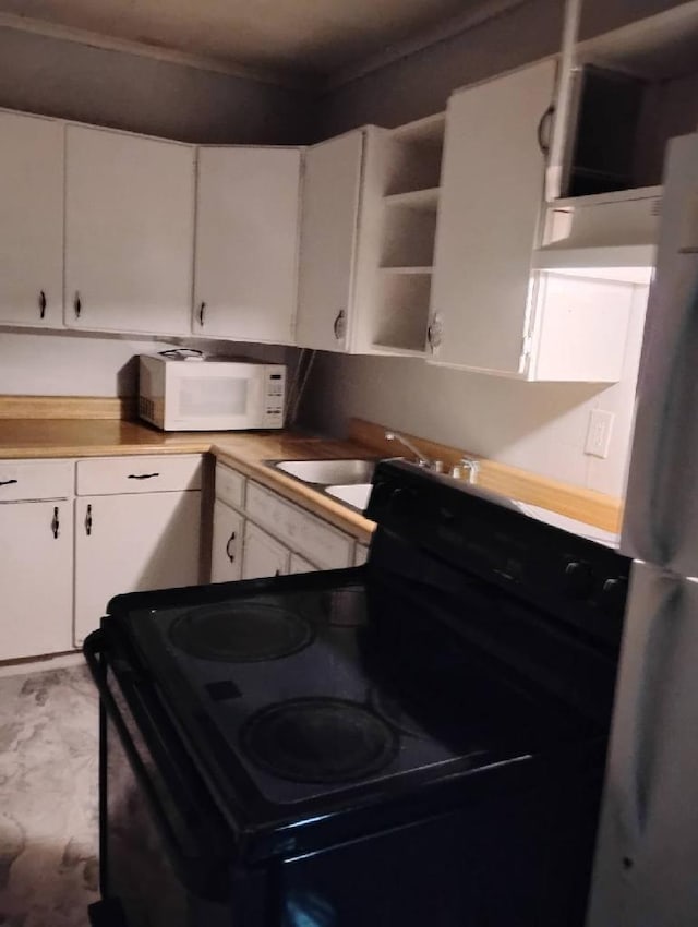 kitchen with sink, white cabinetry, fridge, and black / electric stove