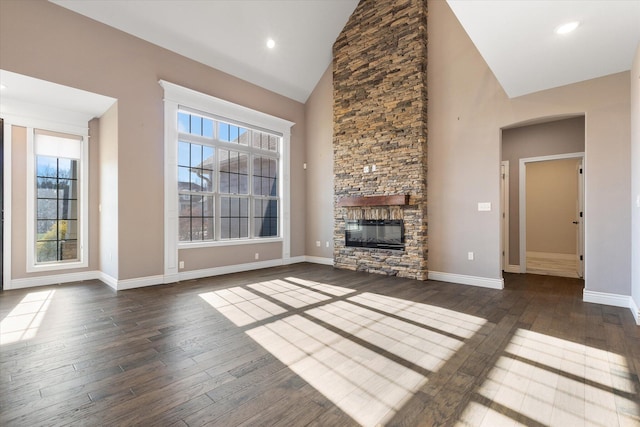 unfurnished living room with a stone fireplace, dark hardwood / wood-style flooring, and high vaulted ceiling