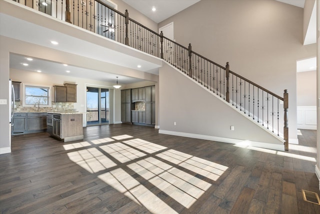 unfurnished living room featuring dark hardwood / wood-style flooring, a towering ceiling, and sink