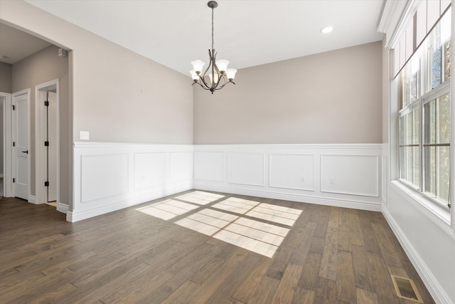 empty room featuring dark wood-type flooring and a chandelier