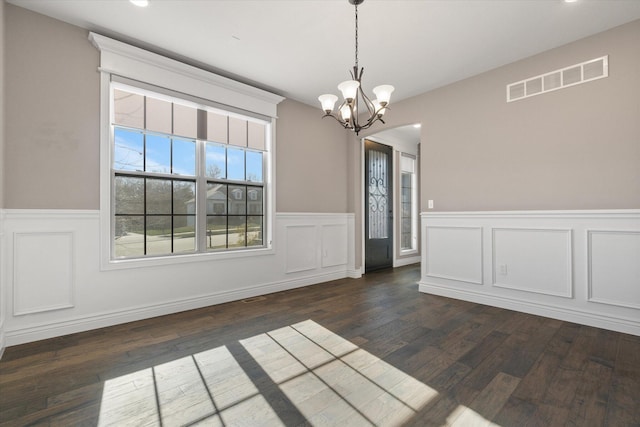 unfurnished dining area with a chandelier and dark wood-type flooring