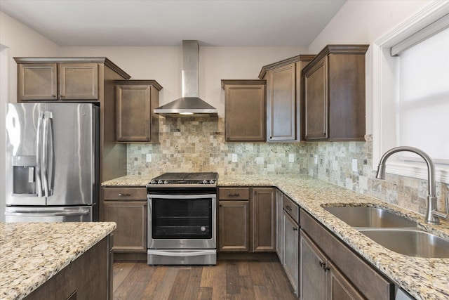 kitchen with light stone countertops, appliances with stainless steel finishes, wall chimney exhaust hood, dark wood-type flooring, and sink