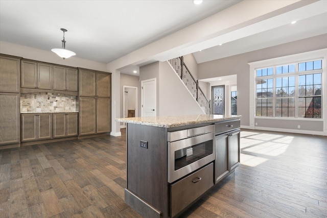 kitchen with dark brown cabinetry, dark hardwood / wood-style flooring, a center island, and pendant lighting