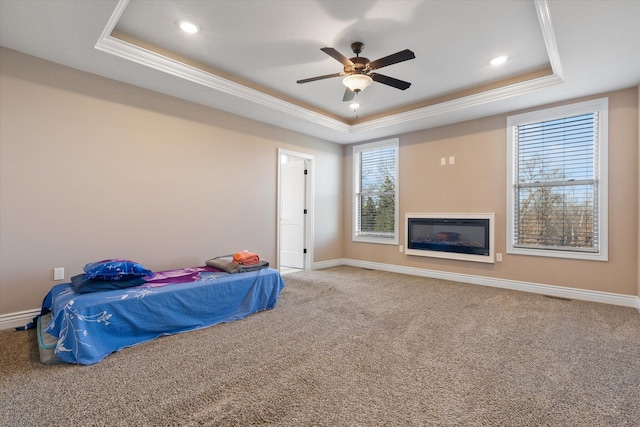 carpeted bedroom with a raised ceiling, ceiling fan, and crown molding