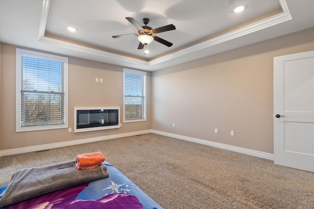 interior space with carpet, a raised ceiling, ceiling fan, and ornamental molding