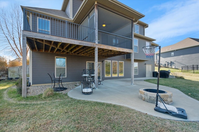 rear view of property with a sunroom, a patio area, a yard, and an outdoor fire pit