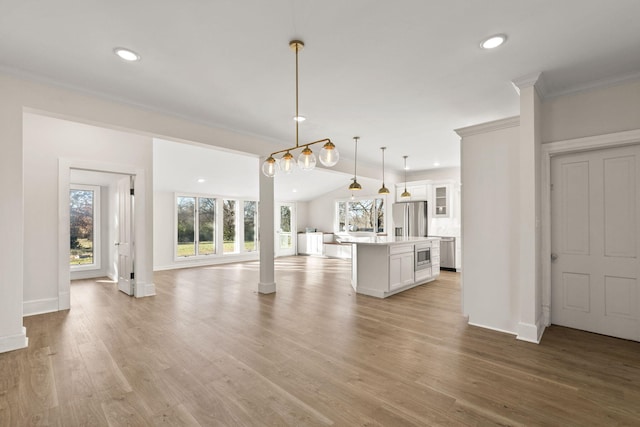 kitchen with a center island, hanging light fixtures, light hardwood / wood-style flooring, white cabinets, and appliances with stainless steel finishes