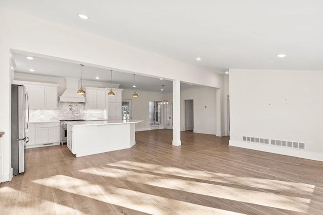 kitchen with a kitchen island, light wood-type flooring, stainless steel appliances, and hanging light fixtures