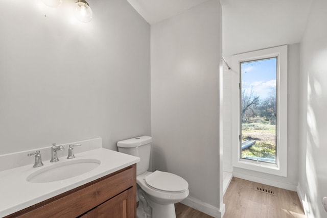 bathroom featuring hardwood / wood-style flooring, plenty of natural light, toilet, and vanity