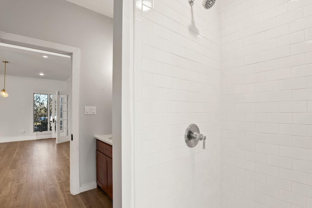 bathroom with crown molding, vanity, wood-type flooring, and tiled shower