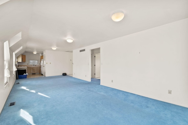 unfurnished living room featuring light colored carpet and vaulted ceiling