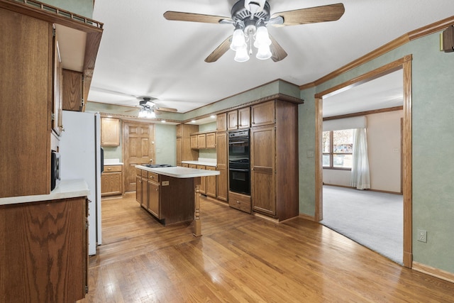 kitchen featuring double oven, crown molding, white refrigerator, light hardwood / wood-style flooring, and a center island