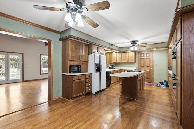 kitchen with hardwood / wood-style floors, black appliances, sink, ornamental molding, and a kitchen island