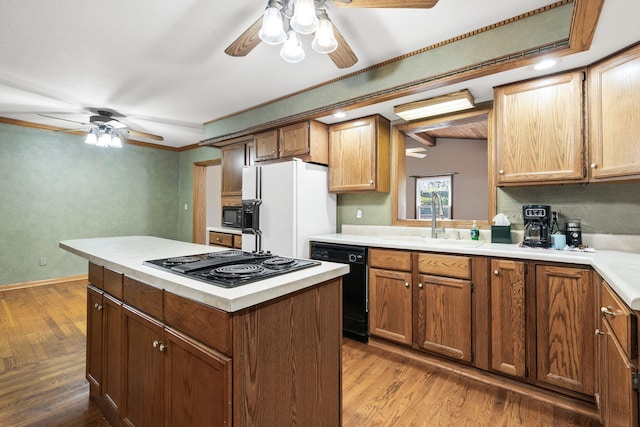 kitchen with sink, black appliances, wood-type flooring, beamed ceiling, and a kitchen island