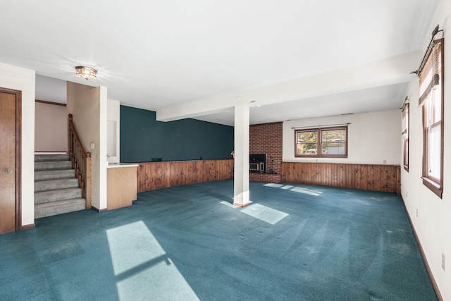 basement with dark colored carpet, wooden walls, and a brick fireplace