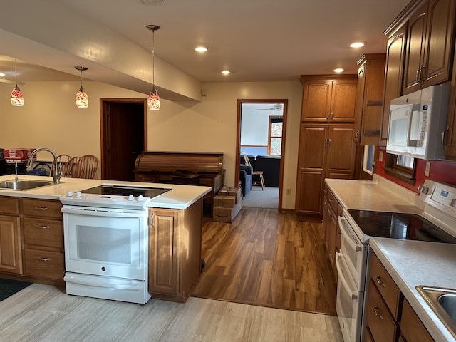 kitchen featuring hardwood / wood-style floors, white appliances, sink, and hanging light fixtures