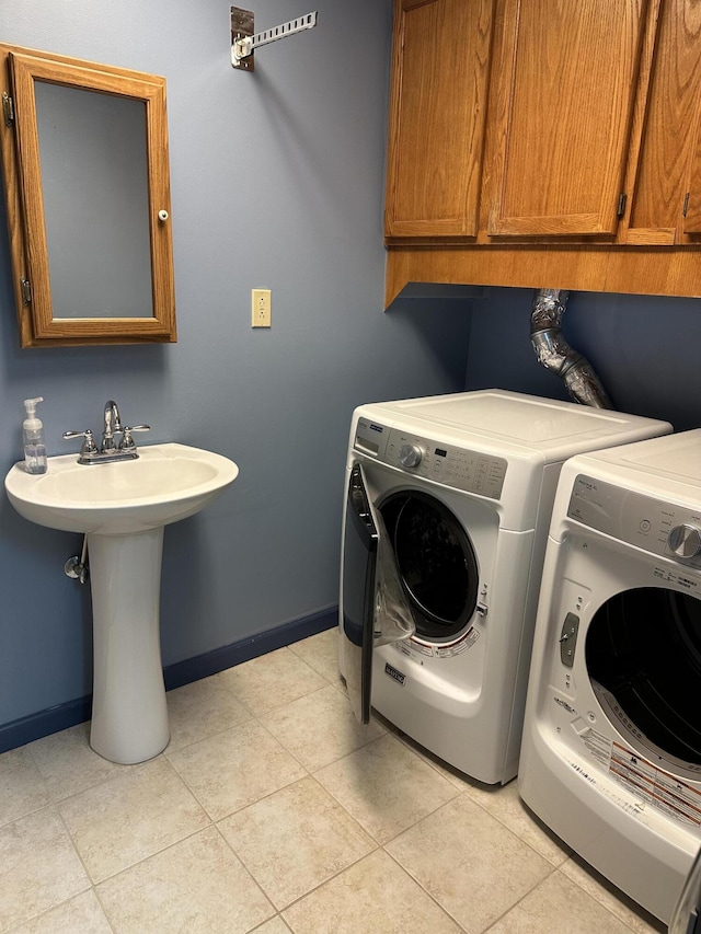 laundry room with cabinets, light tile patterned floors, sink, and washing machine and clothes dryer