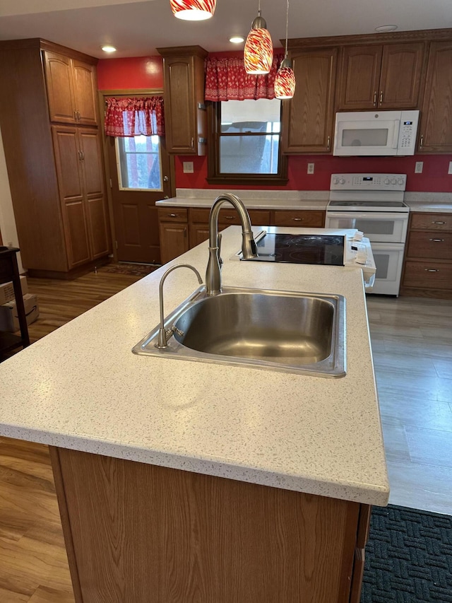 kitchen featuring dark hardwood / wood-style flooring, white appliances, a kitchen island with sink, sink, and pendant lighting