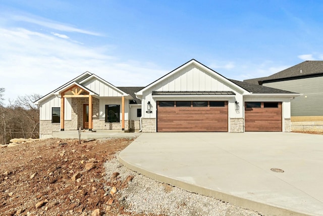 view of front of house featuring driveway, stone siding, a garage, and board and batten siding