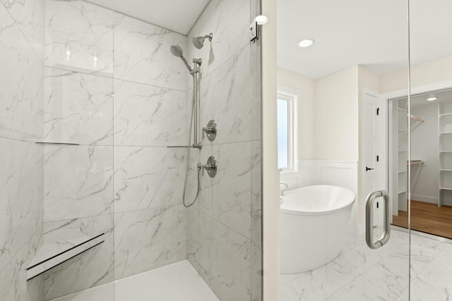 bathroom featuring a freestanding bath, marble finish floor, a spacious closet, wainscoting, and a marble finish shower