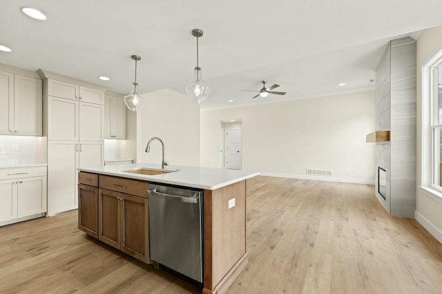 kitchen with light countertops, visible vents, stainless steel dishwasher, light wood-style floors, and a sink