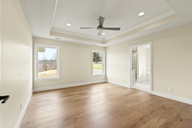 unfurnished bedroom with light wood-style floors, baseboards, a tray ceiling, and recessed lighting