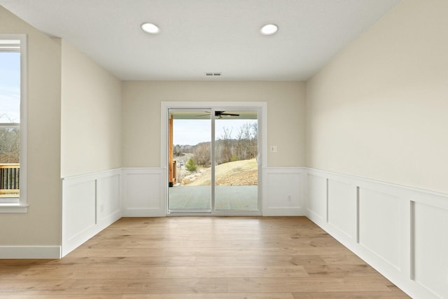 spare room featuring light wood finished floors, visible vents, a wainscoted wall, and recessed lighting