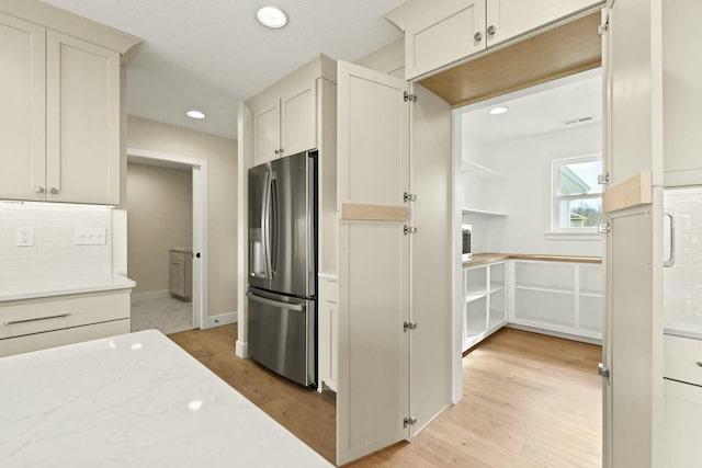 kitchen with stainless steel refrigerator with ice dispenser, recessed lighting, visible vents, backsplash, and light wood-style floors