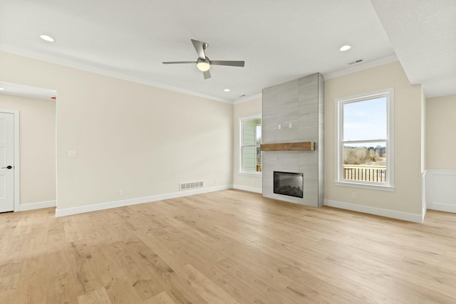 unfurnished living room with a tile fireplace, visible vents, crown molding, and light wood finished floors