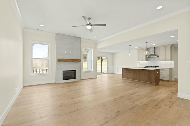 unfurnished living room with recessed lighting, ornamental molding, a ceiling fan, a sink, and light wood-type flooring