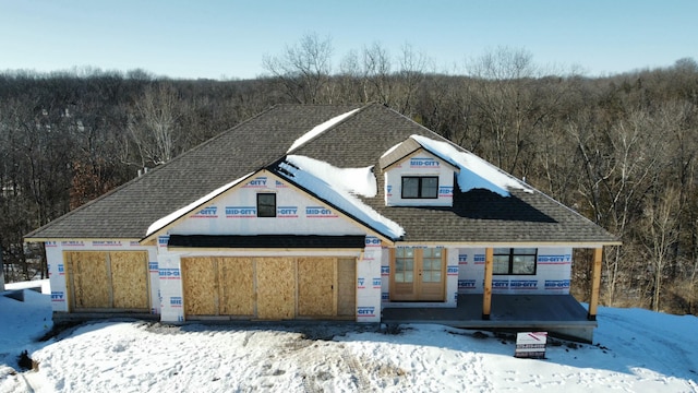 view of front facade with a forest view and a shingled roof