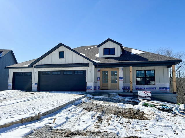 view of front of house featuring an attached garage, roof with shingles, board and batten siding, and french doors