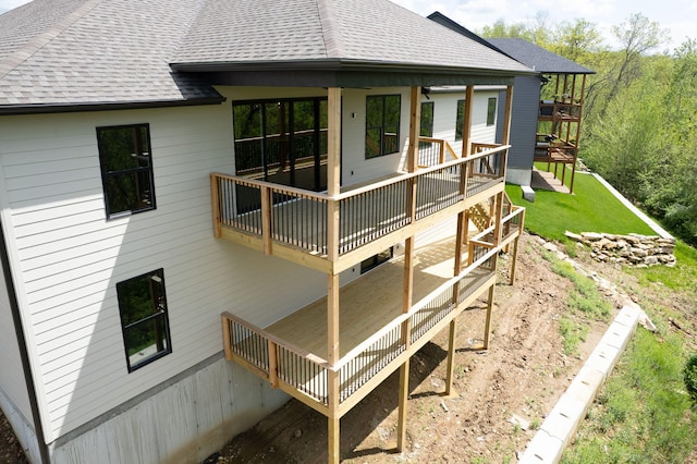 rear view of property with a yard, a deck, and a shingled roof