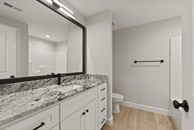 bathroom with vanity, toilet, baseboards, wood finished floors, and visible vents