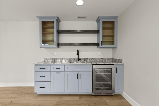 bar with visible vents, beverage cooler, baseboards, indoor wet bar, and a sink