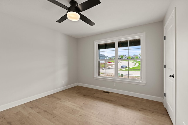 unfurnished room with baseboards, a ceiling fan, light wood-style floors, and visible vents