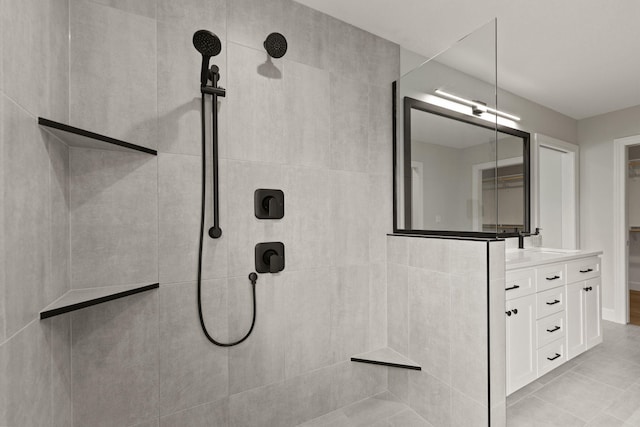 bathroom with tile patterned floors, a tile shower, and vanity