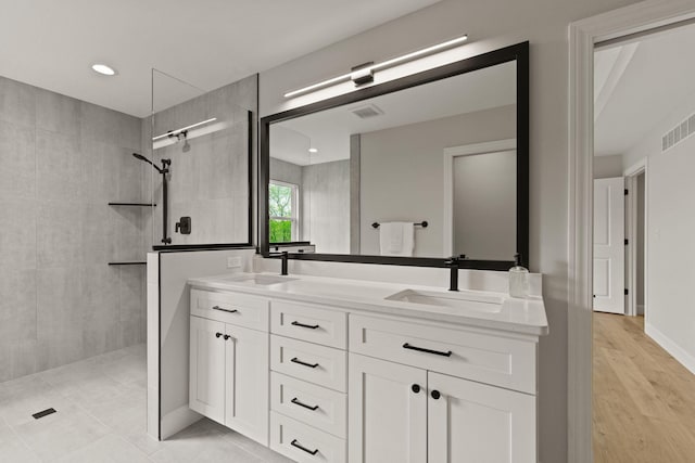 bathroom featuring visible vents, a sink, and a walk in shower
