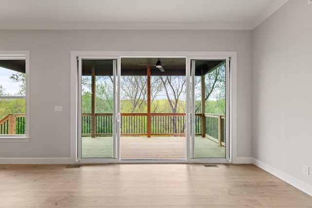 doorway to outside with baseboards, visible vents, ornamental molding, and light wood-style floors