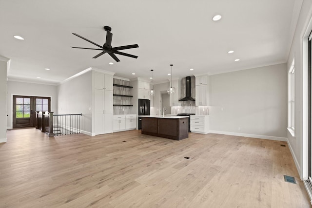 kitchen with open shelves, light countertops, wall chimney exhaust hood, open floor plan, and visible vents