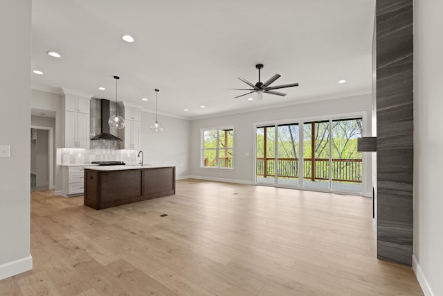 kitchen with ornamental molding, open floor plan, ceiling fan, wall chimney range hood, and recessed lighting