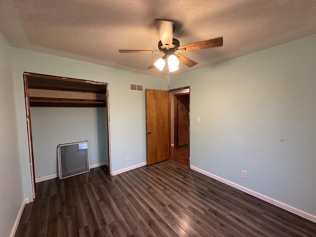 unfurnished bedroom with a textured ceiling, a closet, ceiling fan, and dark wood-type flooring