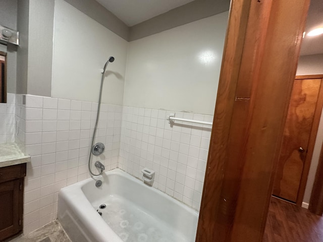 bathroom with shower / bathtub combination, vanity, tile walls, and hardwood / wood-style flooring