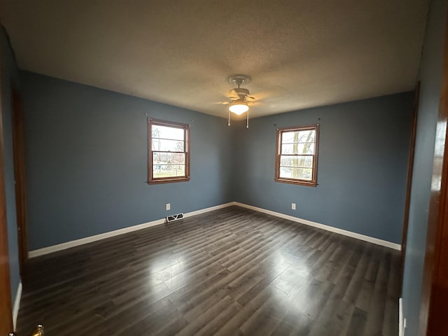 unfurnished room with dark hardwood / wood-style flooring, ceiling fan, plenty of natural light, and a textured ceiling