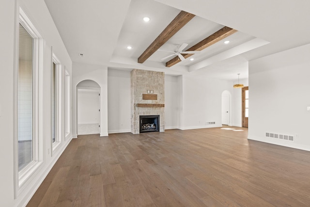 unfurnished living room featuring hardwood / wood-style flooring, a healthy amount of sunlight, a fireplace, and beamed ceiling