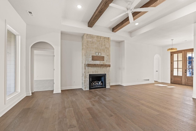 unfurnished living room with hardwood / wood-style floors, a stone fireplace, and french doors